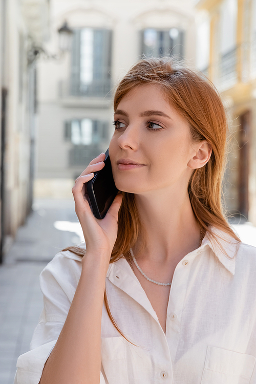 portrait of redhead woman talking on smartphone and looking away in valencia