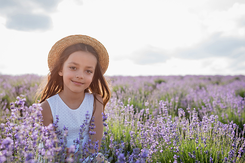 brunette girl in straw hat smiling at camera in lavender field on summer day