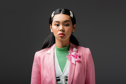 Asian woman with barrettes looking at camera isolated on grey