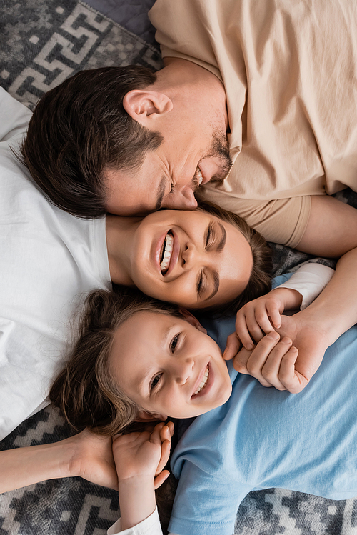 top view of joyful parents and happy kid lying on bed at home