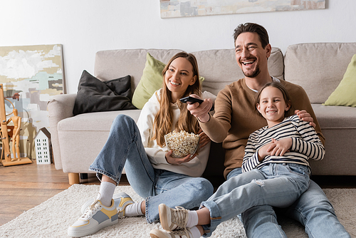 happy man holding remote controller while watching movie with family