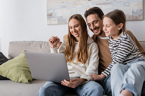 happy family smiling while looking at laptop in living room