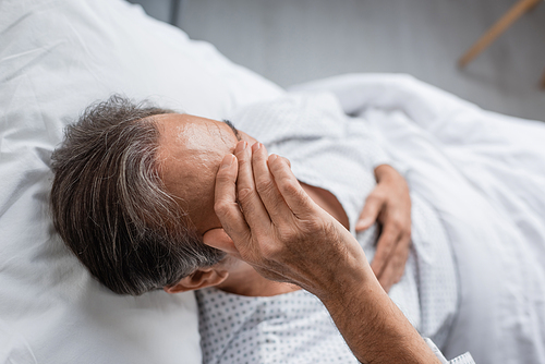 Overhead view of sick elderly man lying on bed in hospital ward