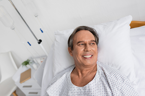 High angle view of cheerful senior patient lying on hospital bed