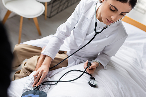 High angle view of doctor checking blood pressure of elderly patient on bed in hospital