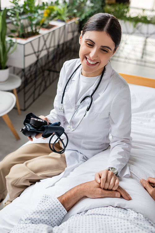 Smiling doctor with tonometer touching hand of senior patient in clinic