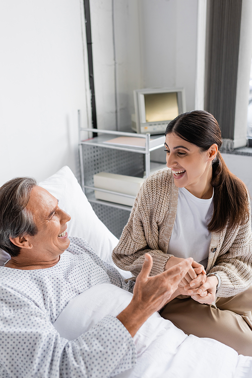 Positive man in patient gown talking to daughter in clinic