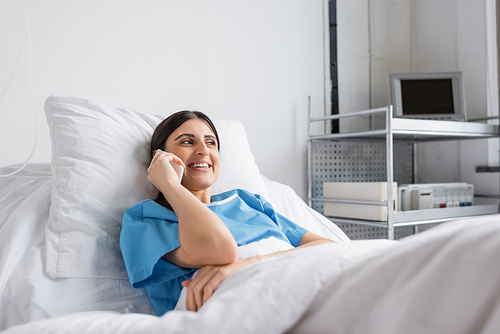 Positive patient talking on smartphone while lying on bed in clinic