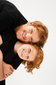young and cheerful man with redhead son having fun while looking at camera isolated on grey