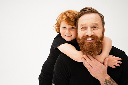 cheerful kid hugging happy bearded grandfather and looking at camera isolated on grey