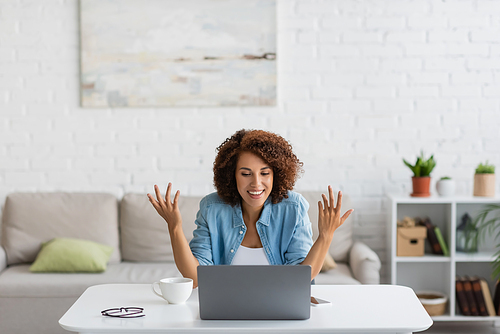 happy african american freelancer gesturing during video call on laptop