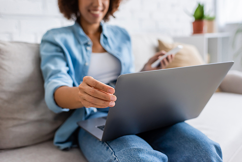 cropped view of african american woman using laptop while sitting on couch