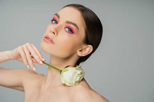 sensual woman with makeup and naked shoulder posing with ivory rose isolated on grey