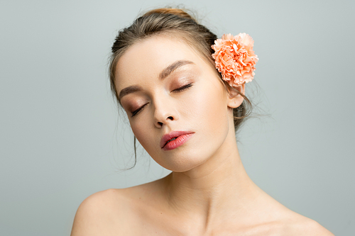 portrait of charming woman with closed eyes and fresh carnation flower behind ear isolated on grey
