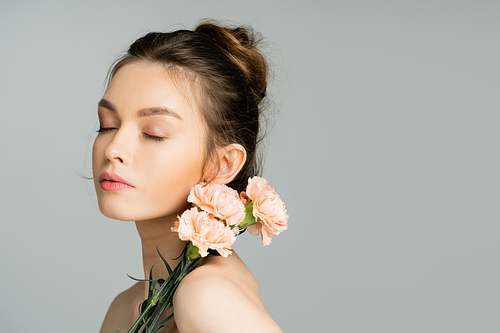 Pretty woman with natural makeup posing with carnations isolated on grey