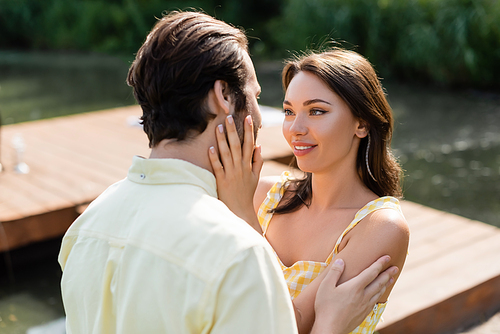 cheerful and sensual woman touching face of boyfriend
