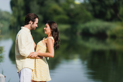 side view of pleased young couple looking at each other near lake