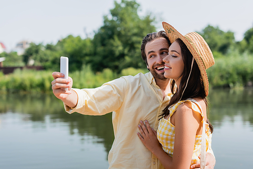 happy young couple taking selfie near lake