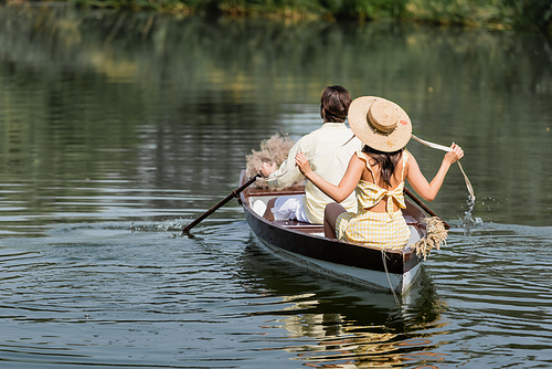 back view of woman in straw hat having boat ride with boyfriend