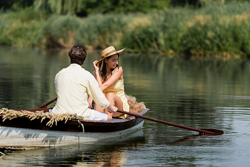 joyful woman in straw hat having romantic boat ride with man