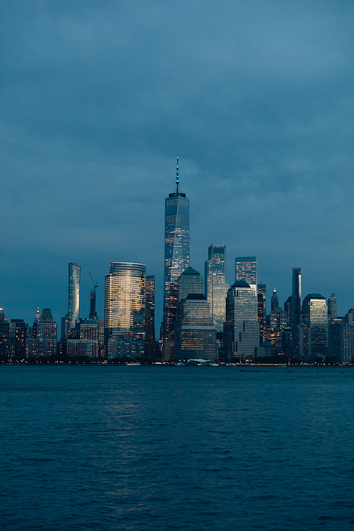 New York harbor and skyline with Manhattan skyscrapers and One World Trade Center in dusk