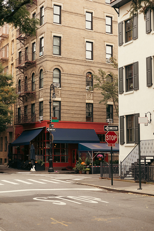 building with cafe near crosswalk and road signs on urban street in New York City