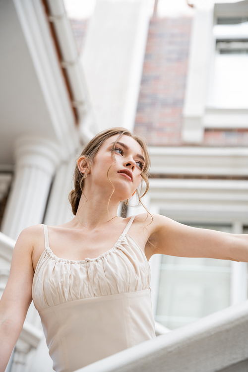 low angle view of young woman in wedding dress looking away near house