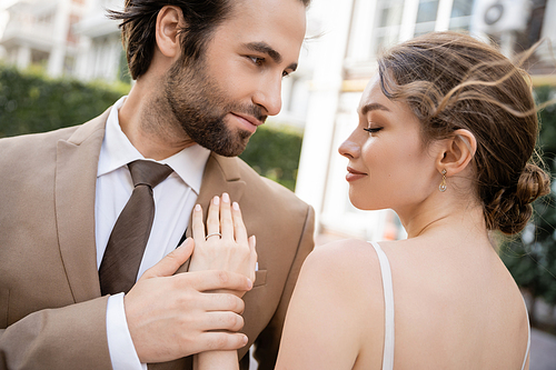 young woman with wedding ring on finger standing with groom in suit