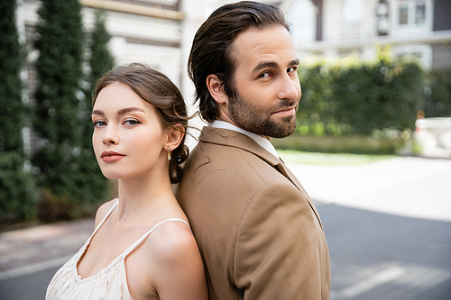 pretty bride in wedding dress and groom in suit standing back to back