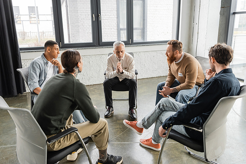 Multiethnic people with alcohol addiction sitting in circle in rehab center