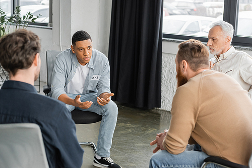 African american man with alcohol addiction sharing problem during group therapy session in rehab center