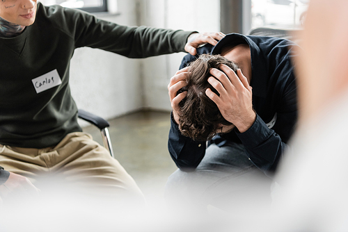 Blurred man calming person with alcohol addiction during meeting in rehab center