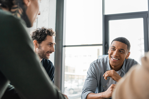 Positive interracial people with alcohol addiction talking during group therapy in rehab center