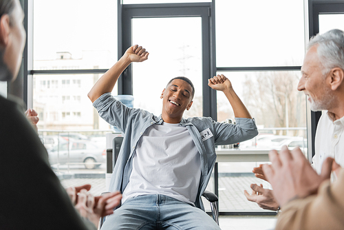 Excited african american man with alcohol addiction showing yes gesture during group therapy session