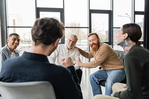 Cheerful interracial group of people with alcohol addiction talking in rehab center