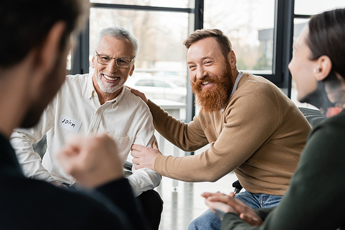 Positive people with alcohol addiction sitting in circle in rehab center