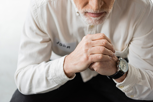 Cropped view of middle aged man with alcohol addiction sitting in rehab center