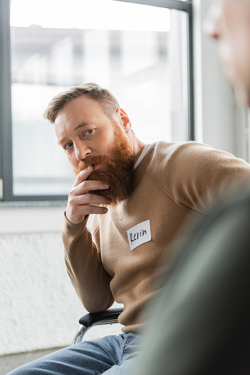 Bearded man with alcohol addiction looking at member of aa group in rehab center