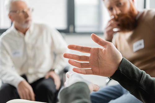 Man sitting near blurred group during alcoholics meeting in rehab center