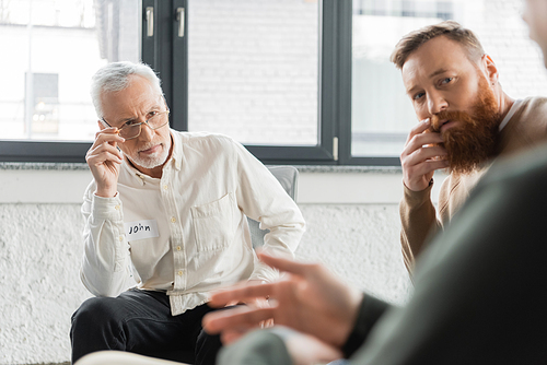 People looking at blurred man during alcoholics meeting in rehab center