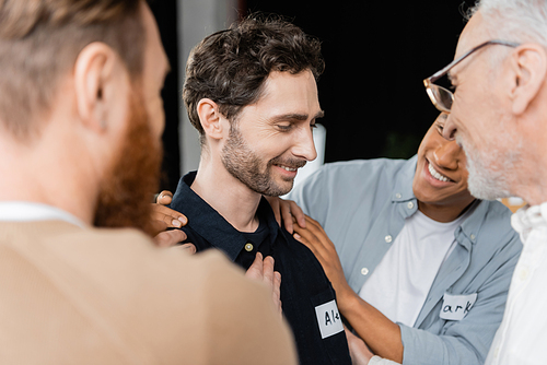 Positive multiethnic people hugging man with alcohol addiction in rehab center