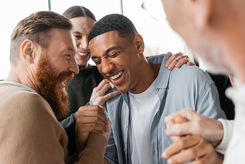 Positive people hugging african american man during alcoholics meeting and therapy in rehab center