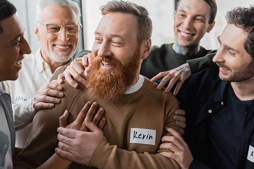 Interracial people hugging smiling man during alcoholics therapy in rehab center