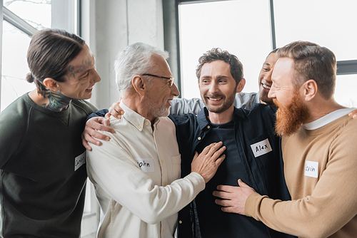 Smiling multiethnic people with alcohol addiction hugging in rehab center