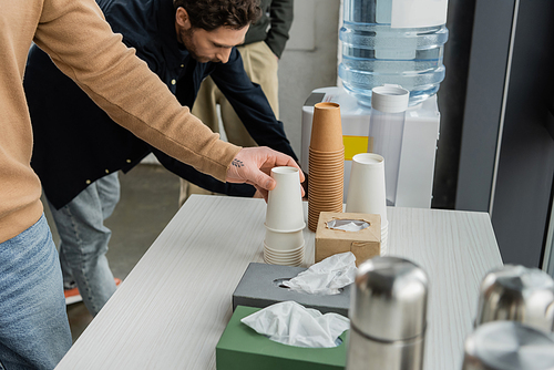 Man with alcohol addiction taking paper cup in rehab center