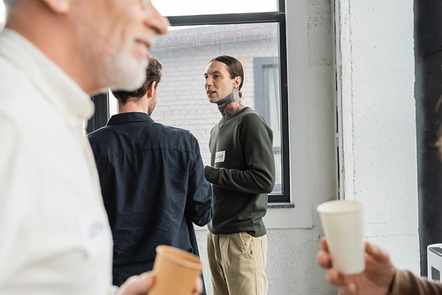 Tattooed man talking to people during alcoholics meeting in recovery center