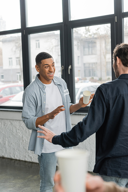 Cheerful interracial men with alcohol addiction talking in recovery center