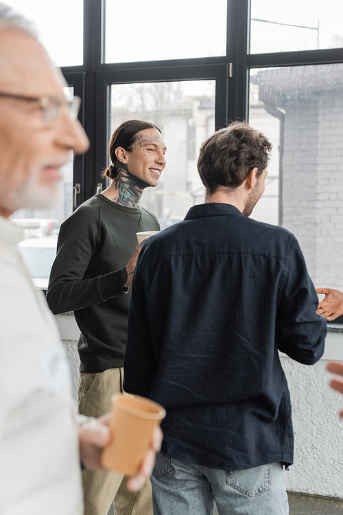 Positive men with paper cups talking during alcoholics meeting in recovery center