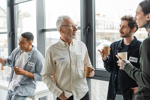 Positive people with paper cups talking during alcoholics meeting in rehab center