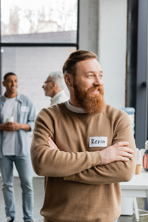 Smiling man crossing arms during alcoholics meeting in recovery center